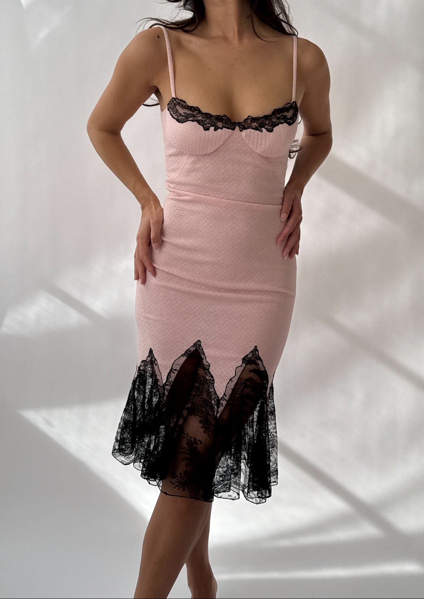 Front view on a model of Versace S/S 2002 pink bodycon dress with black lace mermaid trim.
