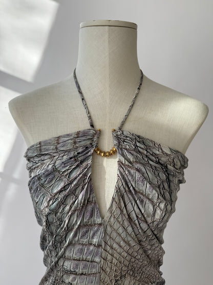 Extreme close-up of crocodile texture and gold hardware on Cavalli mini dress displayed on mannequin.