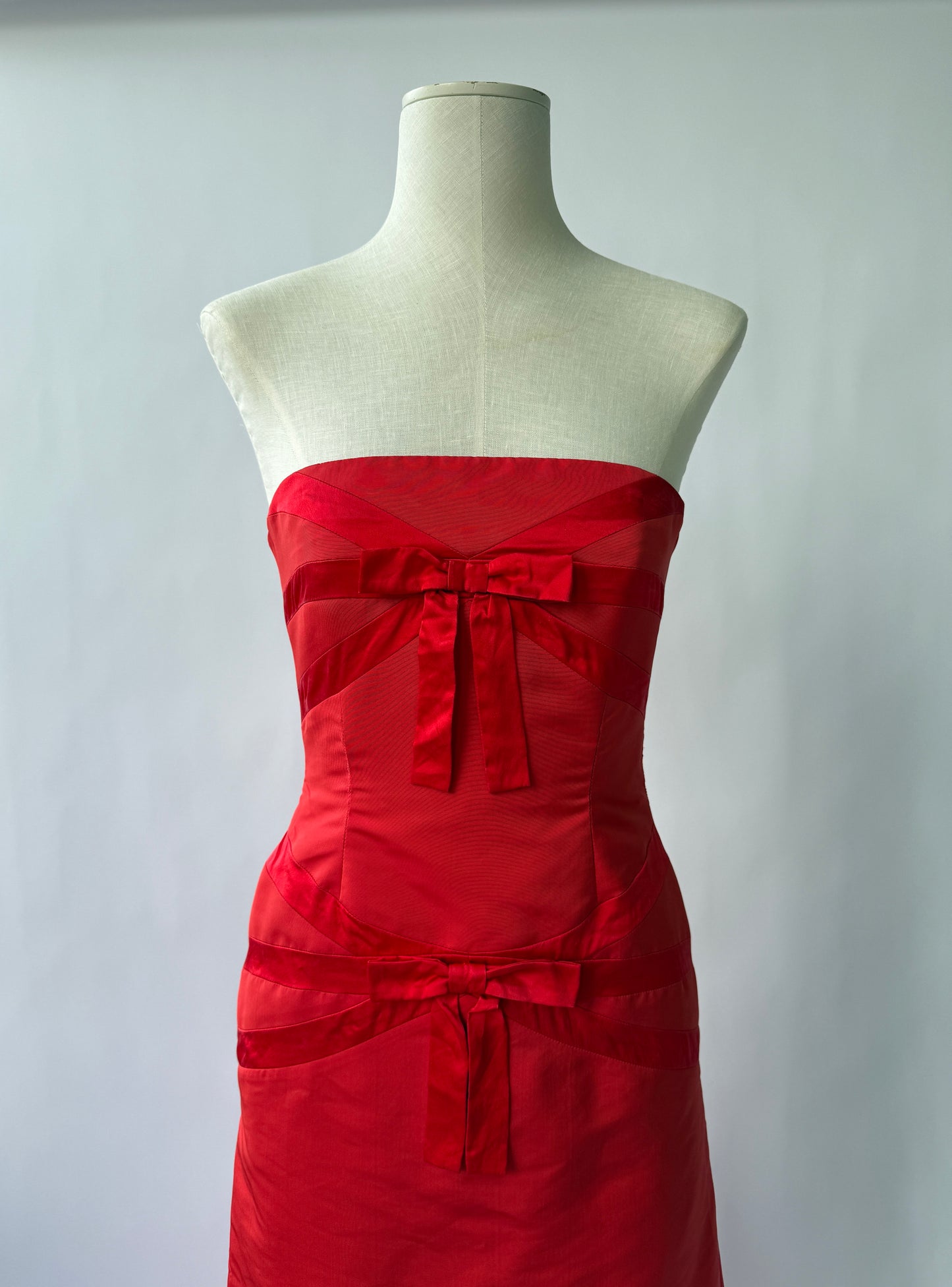 Close up photo of the bodice of the Valentino Strapless Red dress with bows on a mannequin viewed from the front