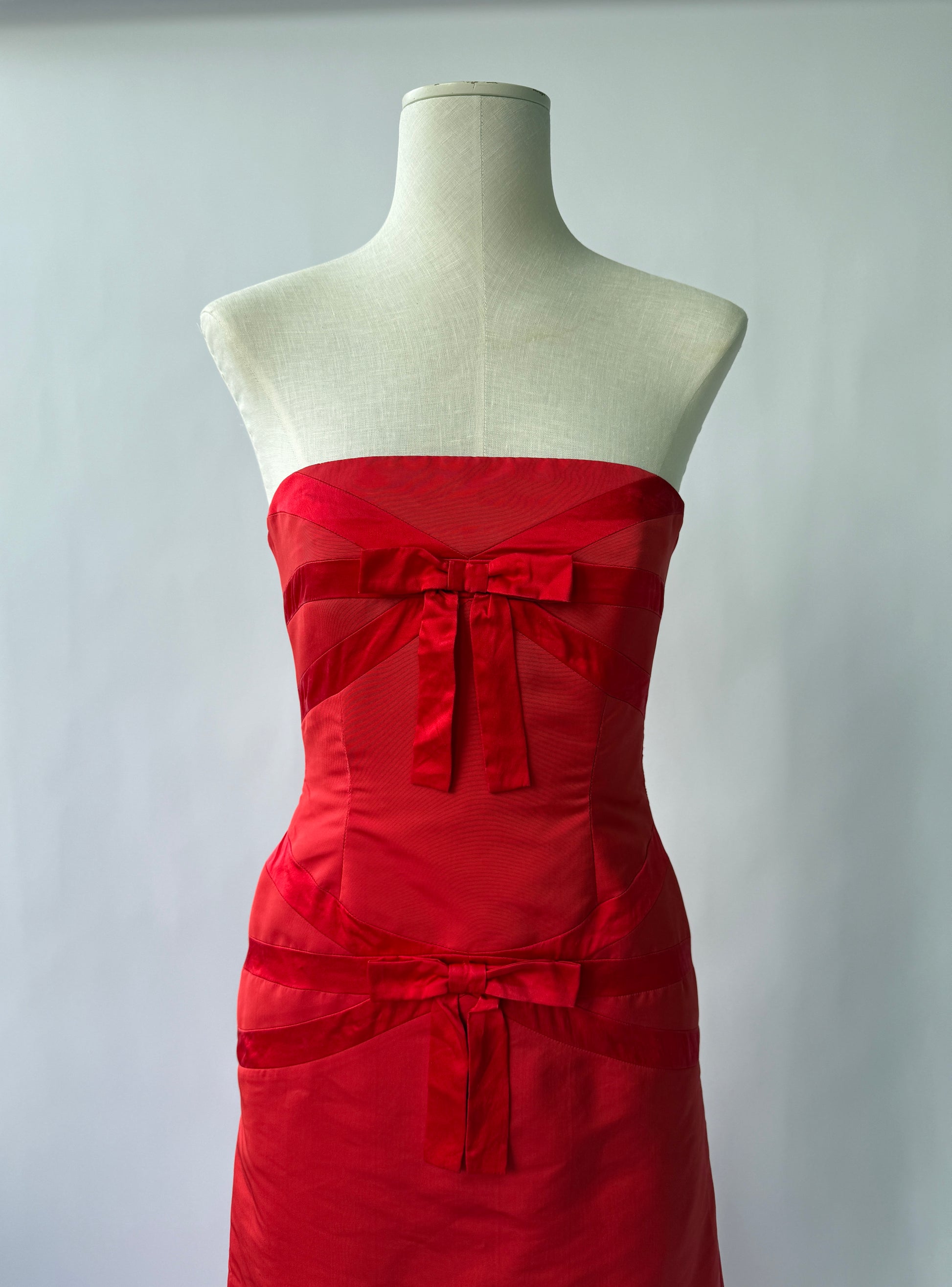 Close up photo of the bodice of the Valentino Strapless Red dress with bows on a mannequin viewed from the front
